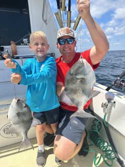 Man poses with child and small fish