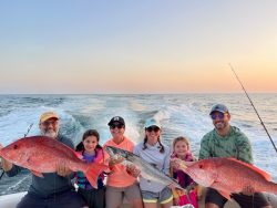 Family holding fish while on a fishing charter boat