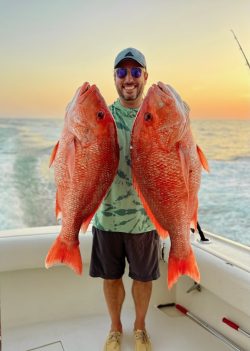 man holding 2 red snapper